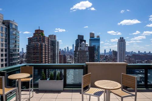 uma varanda com mesas e cadeiras e um horizonte da cidade em Hyatt House New York/Chelsea em Nova Iorque