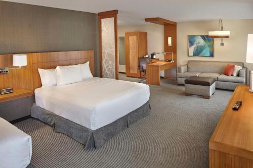 a bedroom with a large bed and a living room at Hyatt Place State College in State College