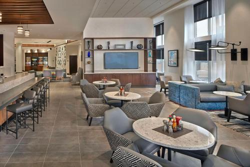 a lobby with tables and chairs and a tv at Hyatt Place State College in State College