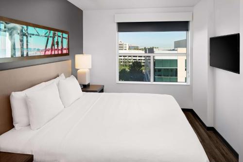 a white bedroom with a large bed and a window at Hyatt House Irvine/John Wayne Airport in Irvine
