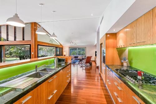 a kitchen with wooden cabinets and green accents at Cabarita Beach Oasis - 3BR Beach House by uHoliday in Cabarita Beach