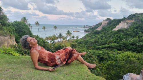 a statue of a man sitting on a hill overlooking the ocean at Camping Harmonia in Conde