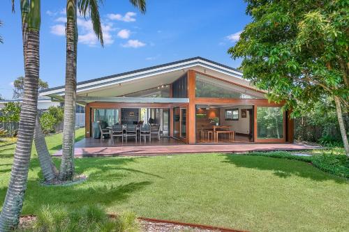 a large glass house with a patio and a yard at Cabarita Beach Oasis - 3BR Beach House by uHoliday in Cabarita Beach