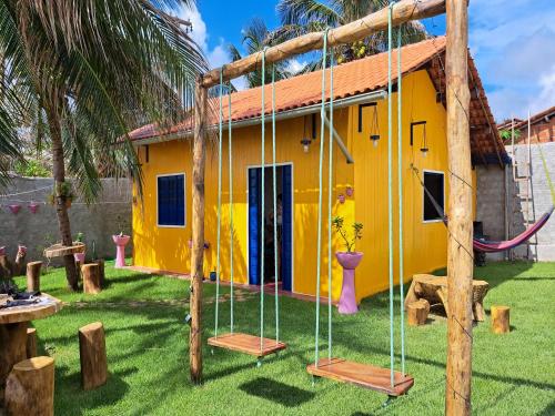 a yellow house with swings in front of it at Casa de Praia Tutóia in Tutóia