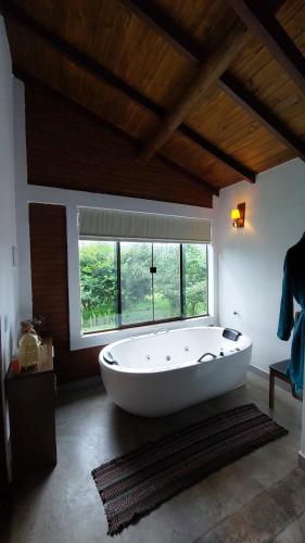 a large white tub in a room with a window at Refúgio no meio da natureza - Chalé Brisa Da mata in Alto Paraíso de Goiás