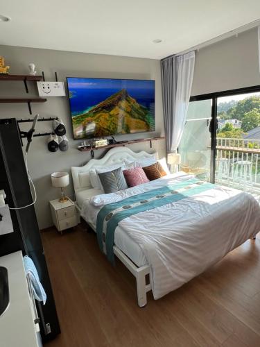 um quarto com uma cama grande e uma televisão na parede em Comfy 2-King Bed Condo - 3 Min to Rawai Beach at The Titile V Condo's em Phuket