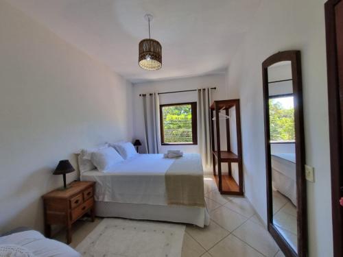 1 dormitorio con cama blanca y espejo en Casa da Dilma Trancoso, en Trancoso