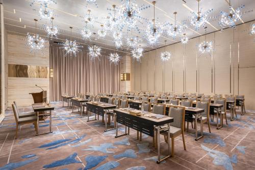 a banquet hall with tables and chairs and chandeliers at Narcissus The Royal Hotel in Riyadh
