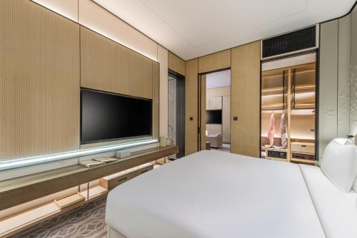 a bedroom with a large bed and a flat screen tv at Narcissus The Royal Hotel in Riyadh