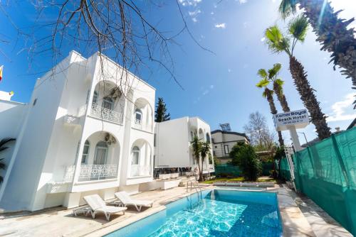 ein weißes Haus mit einem Pool und Palmen in der Unterkunft Kemer Royal Beach Hotel in Kemer