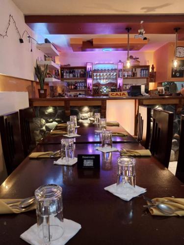 una mesa larga en un restaurante con vasos. en Hostal Restaurante el Fogón Campero en Papallacta