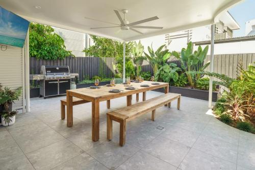 a wooden table and bench on a patio with a grill at Villa Parkana - Beachside Buddina in Buddina