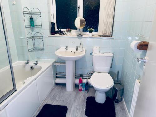 een badkamer met een toilet, een wastafel en een bad bij Home Paradise Manchester- 3 Bedroom House in Manchester
