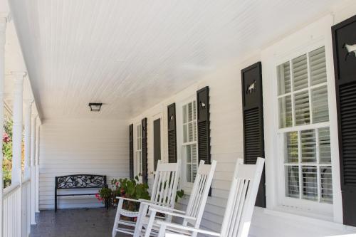 a porch with two white chairs and a bench at Excelsior at the Manor House in Clemmons