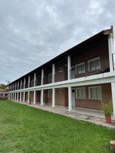 a long brick building with a green lawn in front at Hotel Aimara in Mina Clavero