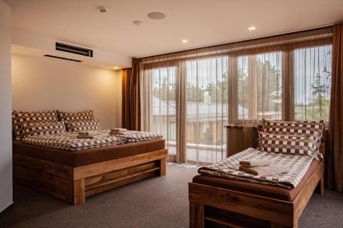 een slaapkamer met twee bedden en een groot raam bij Camelot Ostrava in Radvanice