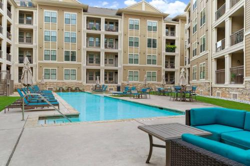 a pool with chairs and tables in a building at Modish King Bed w/ Pool & Gym in Houston