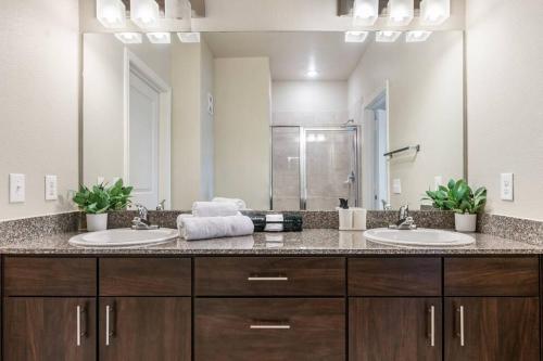 a bathroom with two sinks and a large mirror at Modish King Bed w/ Pool & Gym in Houston