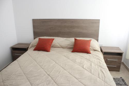 Una cama con dos almohadas rojas encima. en Alojamiento en Chajarí en Chajarí