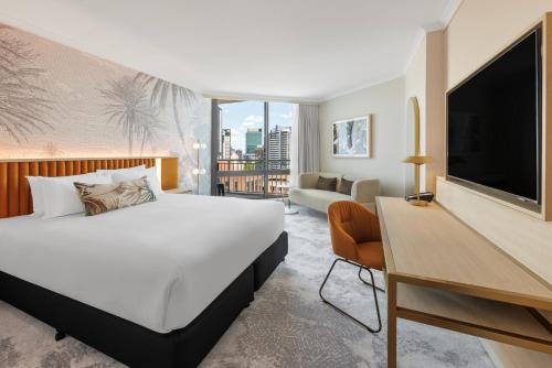 Amora Hotel Brisbane في بريزبين: غرفه فندقيه سرير كبير وتلفزيون
