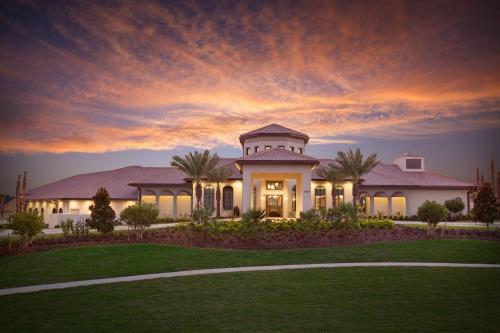 une grande maison blanche avec un coucher de soleil en arrière-plan dans l'établissement Lovely Condos 18 Minutes away from Disney!, à Kissimmee