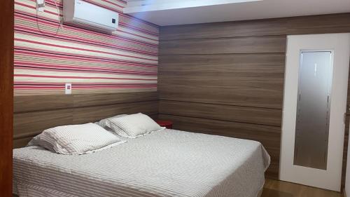a bedroom with a bed with a striped wall at Marina Casa de campo in Santa Maria