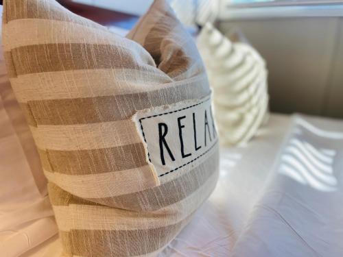 a pillow with the word relax written on it on a bed at Excelsior at the Manor House in Clemmons