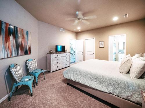 a bedroom with a bed and two chairs and a tv at Cozy 3br Downtown Bakery & Shops! in La Crosse