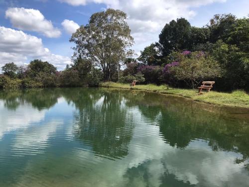 a lake with a bench sitting next to it at Pousada Fazenda São Bento in Alto Paraíso de Goiás