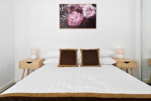 a bedroom with a white bed with two night stands at Executive and Spacious Apartment with Balcony in Sunshine