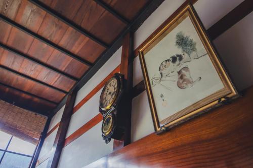 a clock on a wall next to a picture of a dog at 佐渡島 築120年の古民家一棟貸切 河崎浪漫館 囲炉裏体験 檜風呂-蔵サウナ完備 in Sado