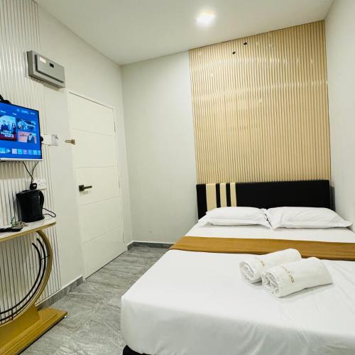 a bedroom with a bed with white sheets and a tv at Rayyaz Inn in Kuala Terengganu