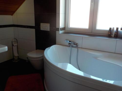 a bathroom with a tub and a toilet and a window at Casa Maika in Frymburk