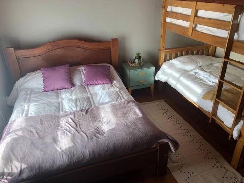 1 dormitorio con 2 literas con almohadas moradas en Departamento cerro de la cruz en Punta Arenas