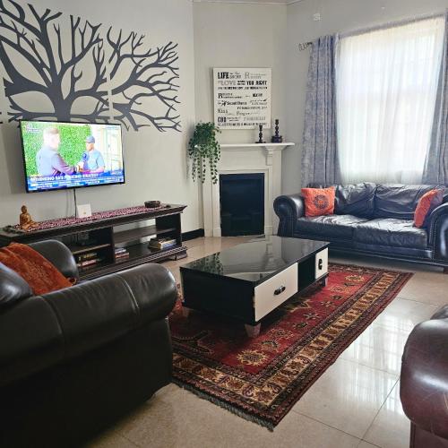 a living room with a couch and a tv at Mukamba Holiday House in Livingstone