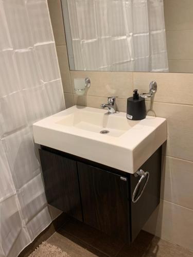 La salle de bains est pourvue d'un lavabo blanc et d'un miroir. dans l'établissement Monoambiente nuevo y luminoso en Flores, à Buenos Aires
