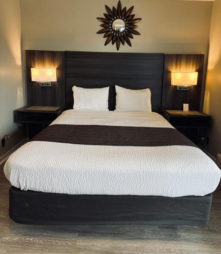 a bedroom with a large bed with two lamps and a clock at Lakeview Motel & Cottage in Kincardine