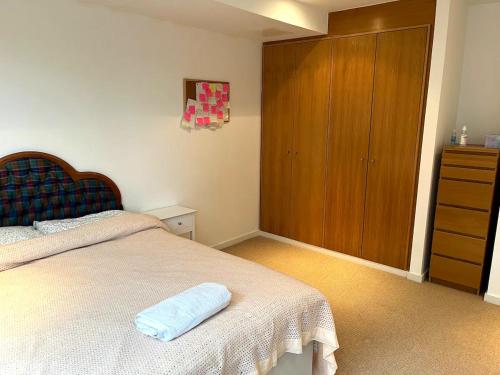 um quarto com uma cama e um armário de madeira em Spacious Queen Bed City Centre Penthouse With Balcony - Homeshare - Live In Host em Glasgow