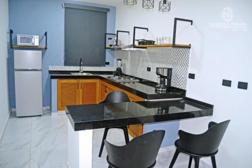 a kitchen with a black counter top and chairs at HOTEL PALENQUE PREMIER in Palenque
