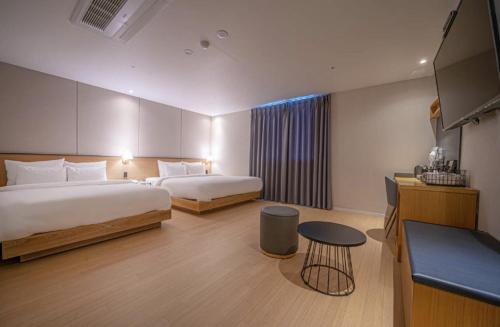 una camera d'albergo con due letti e una televisione di gray195hotel a Gimhae