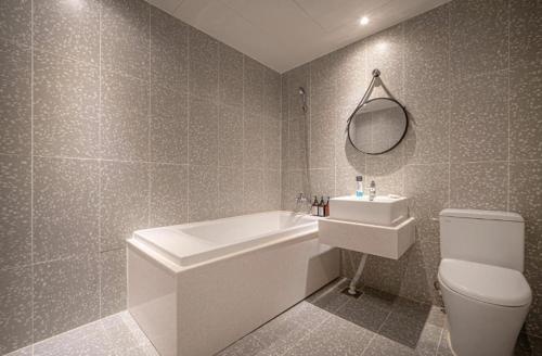 ein Badezimmer mit einer Badewanne, einem WC und einem Waschbecken in der Unterkunft gray195hotel in Gimhae