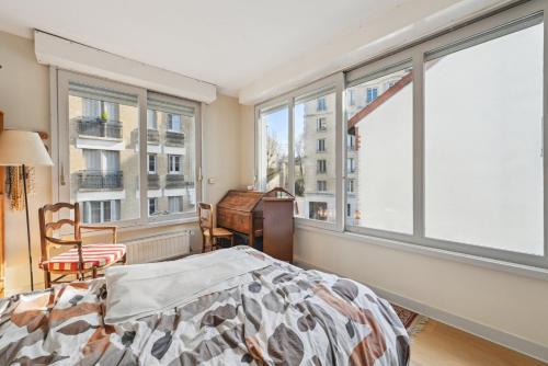 une chambre avec un lit et de grandes fenêtres dans l'établissement La Demeure - Maison de 180m2 à Porte de Versailles, à Paris