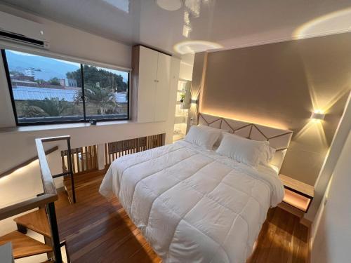 a bedroom with a white bed and a large window at 'SELECT' Medellin in Medellín