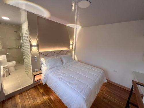 a bedroom with a white bed and a bathroom at 'SELECT' Medellin in Medellín