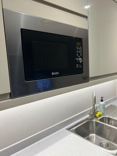 una cucina con forno a microonde sopra un lavandino di Cozy Intimate Apartment - Leeds a Leeds