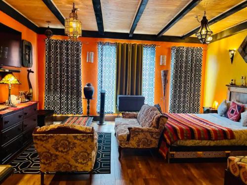 ein Schlafzimmer mit orangefarbenen Wänden und einem Bett und einem Sofa in der Unterkunft Gîte du monde in Québec