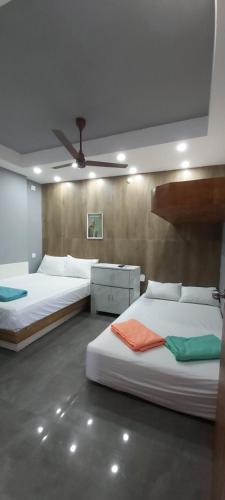a bedroom with two beds and a ceiling fan at HYTON GRAND in Urapakkam