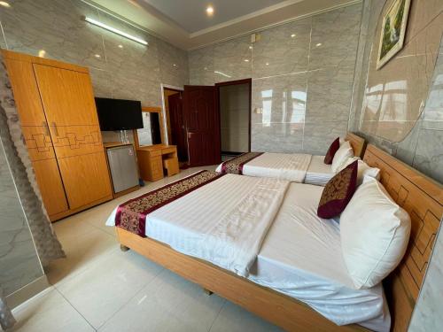 a bedroom with two beds and a television in it at Hồng Nhung Hotel Kiên Giang in Rach Gia