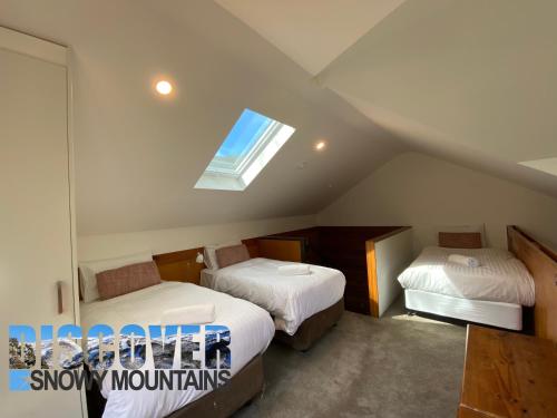 a attic room with two beds and a window at Ramshead Creek 3 in Thredbo