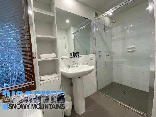 a white bathroom with a sink and a shower at Ramshead Creek 3 in Thredbo